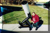 SLAS member Siegfried Jachmann poses next to the 1/3 scale model of the 81 cm (32") telescope to be installed in the Harmons Observatory at SPOC 2.  Note the position of the eyepiece.  As the telescope utilizes a Springfield mount the eyepiece remains in the same place regardless of where the telescope is pointed. 27 NOV 2000